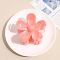 Detail of pink marble floral hair claw clip on ceramic plate with elegant design - Orange