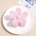 Close-up of pink flower hair claw clip with marble texture on a decorative plate - Pink