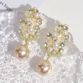 Primer plano detallado de pendientes de perlas color champán y cristales sobre vidrio - Flor de Perla Champaña Diamante