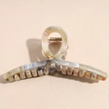 Detailed close-up of large marble texture hair claw clip with golden metal spring - Calico