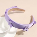 Dettaglio cerchietto in raso viola con perle eleganti su uno sfondo crema delicato - Viola