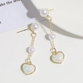 Detalle de los pendientes de cadena dorada con perlas blancas y colgantes de corazón - Corazón de Borla Y Perla