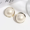 Detalle macro de aretes de perlas geométricas crema con elegante borde de metal dorado - Perla Redonda Irregular