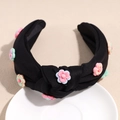 Detail of a black knotted headband with colorful 3D resin flowers on a ceramic dish - Black