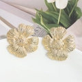 Detalle de pendientes de flores doradas con acabado texturizado en un plato de porcelana - Flor Dorada