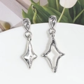 Detalle de pendientes largos asimétricos plateados con formas de rombo y acabado con textura - Estrella de Cuatro Puntas Asimétrica