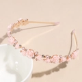 Détail des roses en résine rose et des perles sur un serre-tête floral doré chic - Rose