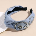 Dettaglio del cerchietto annodato in tessuto blu con borchie argento e perle eleganti - Blu