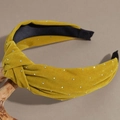Detail eines senfgelben Samtstirnbands mit Knoten und Strasssteinen auf einem Zweig - Gelb