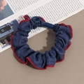 Dettaglio di uno scrunchie in denim blu retrò con pois bianchi e cuciture rosse - Blu scuro