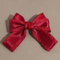 Close-up of a red silk bow hair clip with ruffled edges and shiny satin texture - Red