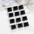 Dettaglio di 12 mini mollette per capelli nere a forma di corona su sfondo bianco - Piccolo Quadrato Nero