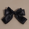 Detailed view of black satin bow hair clip with ruffle edges and dual-layer structure - Black