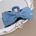 Detail einer blauen Denim-Schleifen-Haarklammer mit Goldetikett auf Vintage-Spiegel - Blauer Denim-Haarkralle