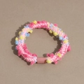Detailed macro view of colorful woven plush hair tie with vibrant dopamine-style pom-poms - Deep Pink