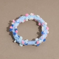 Detail of blue knitted hair tie featuring colorful pom-poms and smooth plastic joint - Blue