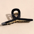 Dettaglio di un grande fermaglio per capelli nero in acrilico con molla in metallo dorato - Nero