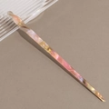 Detailed view of the twisted tortoiseshell acetate hair stick with pearlescent pink texture - Iridescent Yellow-Pink