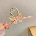 Détail d'une grande pince à cheveux papillon dorée avec texture d'ailes en résine beige - Rose