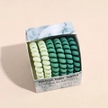 Dettaglio di sei elastici a spirale verdi ad alta elasticità in una scatola marmorizzata - Serie Verde