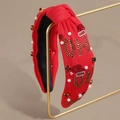Dettaglio ravvicinato di un cerchietto rosso annodato con strass e perle festive - Rosso