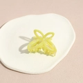 Dettaglio di un fermaglio per capelli a farfalla giallo limone con finitura perlata - Giallo