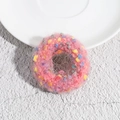 Detail van roze pluchen haarelastiekje met kleurrijke pompons op een wit bord - Roze