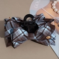 Detail of tartan ribbon hair claw clip featuring brown and blue plaid and a golden logo tag - Plaid Bow Claw Clip
