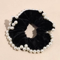 Detail of black velvet scrunchie with white pearl trim decoration on beige background - Black