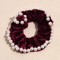Detailed close-up of dark red velvet scrunchie with elegant faux pearl embellishments - Fuschia