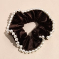 Detailed macro of dark brown velvet scrunchie decorated with white imitation pearls - Coffee