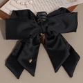 Elegante pinza para el pelo con lazo de satén negro y detalle dorado en fondo madera - Estilo de Lazo con Cinta