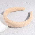 Close-up of beige knitted headband showing thick textured cable stitch and inner lining - Pink
