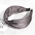 Detailed view of dark grey satin knotted headband with elegant silky luster on white stone - Gray
