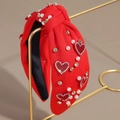 Détail d'un serre-tête noué rouge orné de cœurs en strass et de perles élégantes - Cœur en Perle et Strass Rouge