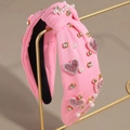 Détail d'un serre-tête rose en tissu avec cœurs pailletés, perles et strass sur support - Cœur en Perle et Strass Rose