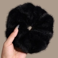 Détail d'un chouchou en fausse fourrure noire avec une texture douce et volumineuse - Noir
