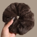 Détail d'un grand chouchou en fausse fourrure marron foncé montrant sa texture douce - Marron
