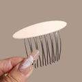 Detailed close-up of cream acetate hair comb with polished metal teeth held in hand - Small Linear Beige