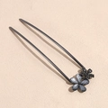 Dettaglio macro di una forcina a U in metallo canna di fucile con fiori opachi e strass neri - Fiore