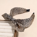 Close-up of leopard print bow headband on a display stand with non-slip wide band detail - Small Leopard Orange