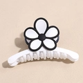 Détail d'une pince à cheveux blanche avec fleur à bord noir et finition en résine mate - Blanc avec Fleur