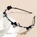 Detail shot of black velvet headband with clear gemstones and pearls on white ceramic - Black Bow