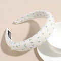 Detailaufnahme des blauen Blumen-Haarreifens mit handgefertigtem schwarzen Stoffetikett - Beige Blumenmuster