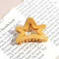 Macro shot of star-shaped orange hair claw with silver glitter finish and metal spring - Pentagram / Orange Yellow (Splash Ink)