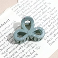 Detailed macro shot of a gray-green hair claw with silver splattered pattern on book pages - Three-Petal Flower / Gray Green (Splash Ink)