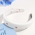 Close-up of a white padded headband with red strawberry embroidery and handmade label - White Strawberry