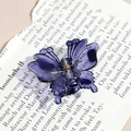Macro detail of a dark purple butterfly hair claw clip on vintage book pages background - Purple Butterfly