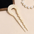 Close-up of elegant cream marble acetate U-shaped hair fork on a wooden tray - Beige
