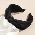 Dettaglio di elegante cerchietto in raso nero con nodo e ornamento di strass scintillanti - Nero